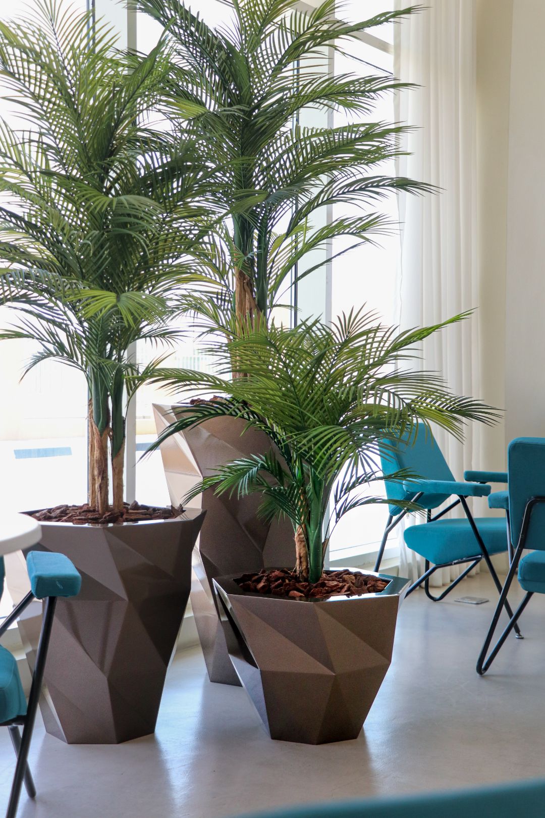 Bronze Taqa trio with areca palms in a hotel lounge